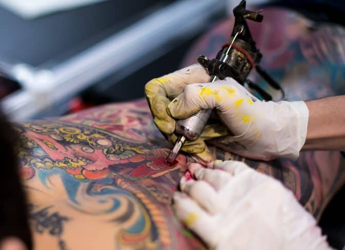 Tattooer tattooing a man